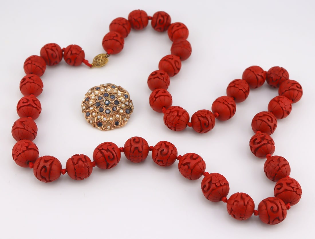 JEWELRY. 14kt Gold, Pearl and Gem Brooch/Pendant.: 14kt yellow gold circular brooch of pierced design displaying pearls and round faceted blue gems - apparently unmarked. Accompanied by a single strand of individually knotted cinnabar style carved bea