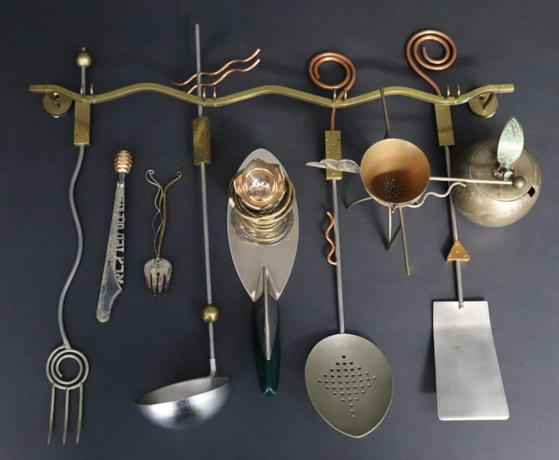 Assorted Eclectic Kitchenware.: Including an unsigned metal rack suspending four (4) mixed-metal assorted kitchen tools; an unsigned mixed-metal modernist tea strainer with stand; a signed stainless steel and plastic modernist cake/