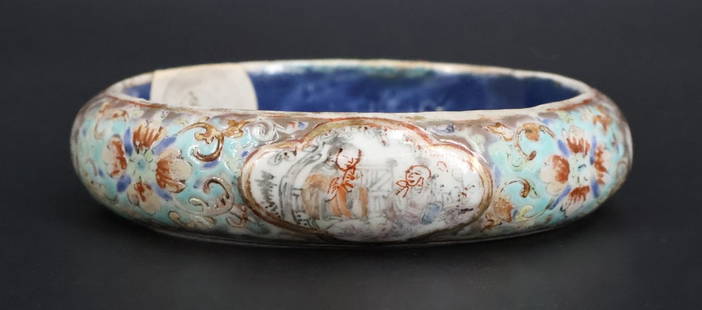 Chinese Enamel Decorated Bangle.: A Chinese enamel decorated porcelain bangle bracelet displaying scenes of figures, flowers, and gardens. The interior label from CY Tse Antiques reads, "19th C 1862- 1875". The interior of t