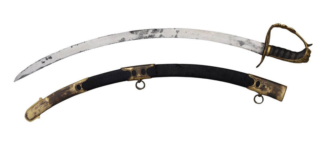 1803 Pattern British Riflemen’s Flat Blade Saber.: A fine and scarce British Riflemen’s 1803 pattern, featuring a flat blade of pronounced curvature and lacking a fuller. The saber is accompanied by its original leather scabbard fitted with two