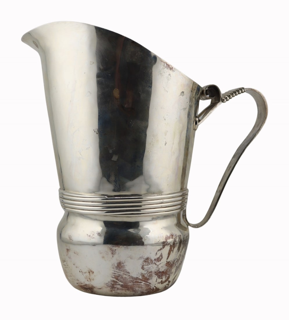 STERLING. William Spratling Mexican Sterling: Pitcher. William Spratling sterling pitcher with ribbed detailing and a slightly curved handle with scroll top. Stamped within a circular mark, "Spratling Made in Mexico" around a conjoined