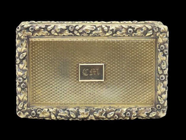 SILVER. Early Victorian English Gilt Silver Snuff: Box. An English gilt silver hinged presentation snuff box, crafted with a detailed oak leaf and acorn border surrounding machined panels. The lid features an applied high-polished rectangular cartouch