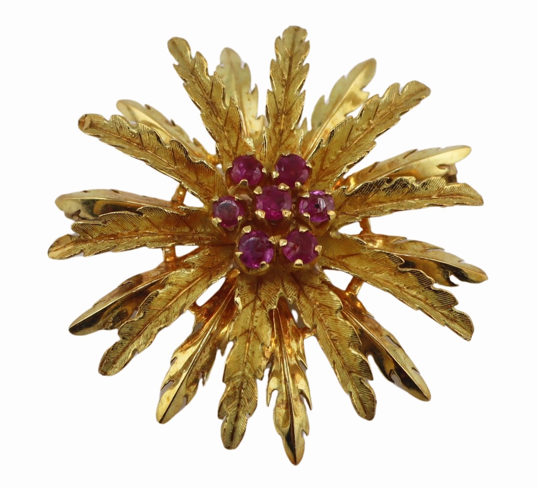 JEWELRY. 18kt Gold and Ruby Starburst Brooch.: 18kt yellow gold starburst form brooch with central cluster of round faceted rubies. Each ruby measures approx. 2.5mm each. Stamped, "750". Total approx. weight of the brooch is 7.7 dwt (gro