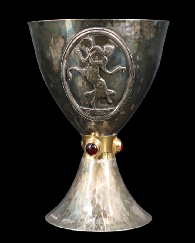 JUDAICA. Yemini Sterling Miriam Kiddush Cup.: A well executed Yemini sterling silver Kiddush cup featuring a hammered surface, with a high polish finish. The stem is accented with a gilt band set with three bezel-set red gems. The cup’s bod