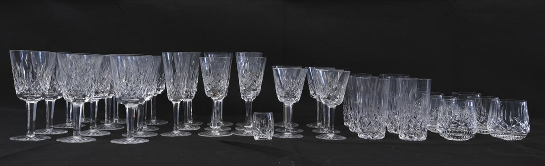 32 Pieces of Waterford Stemware: Waterford stemware as follows: 12 (6.75") water glasses, 7 (7.25") champagne, 6 (6") white wine (?), 6 (3.25") roly poly, 1 (2.25") shot glass plus 6 (5.25") highball, 2 (6 7/8") unsigned. From a New