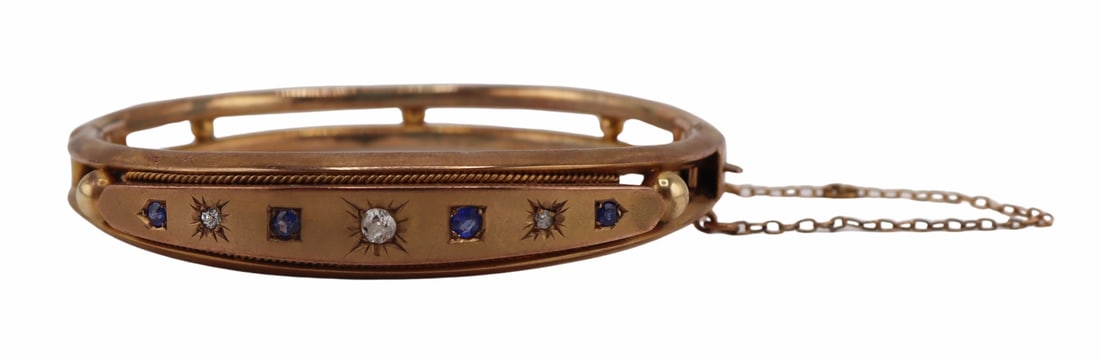 JEWELRY. Victorian 9ct Gold, Sapphire and Diamond: Hinged Bracelet. Victorian 9ct yellow gold hinged bracelet accented by a central band of alternating star set Old Mine cut diamonds and round faceted sapphires. With safety chain. Accompanied by a fit