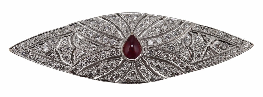 JEWELRY. Art Deco 18kt Diamond and Ruby Brooch: Art Deco 18kt white gold lozenge form brooch displaying a central pear form ruby cabochon surrounded throughout with round full cut diamond accents. Ruby measures approx. 5.5mm x 4.0mm. Stamped, "