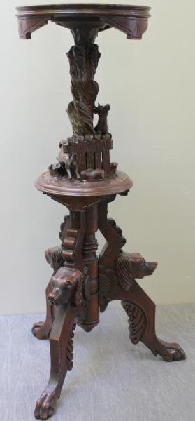 19th Century Black Forest Carved Walnut Pedestal.: With deer and dog motif. Well carved dog's heads around base. From a Yonkers, NY home. Dimensions: 35.675" h. Condition: Good, missing one antler.