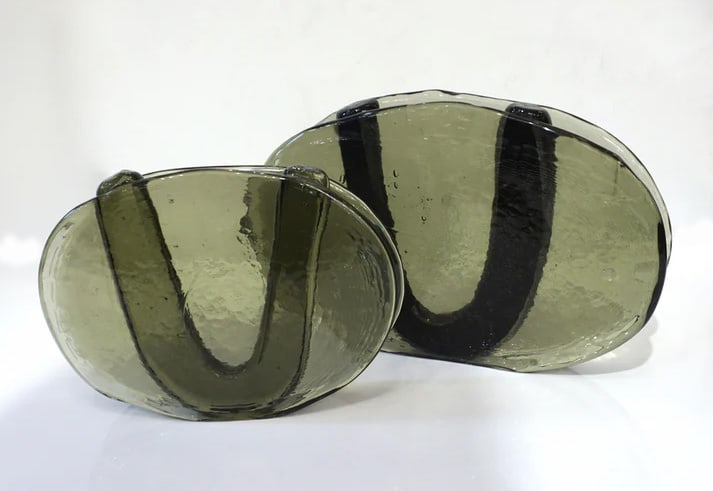 (2) 1970's Italian Smoked Murano Glass Vases.: Minimalist 1970s flower vses in blown smoked green Murano glass, with a slight hammered texture, a very innovative modern design in oval shape, the central part for the flowers is embraced by a black
