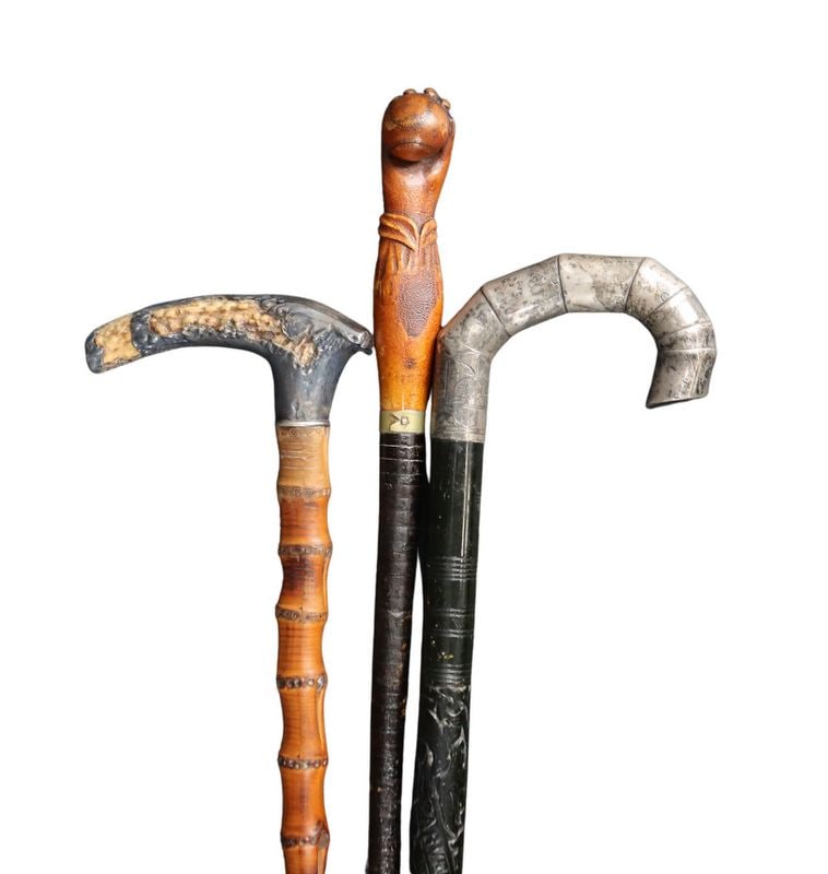 (3) Assorted Canes and Walking Sticks.: Including an engraved bamboo cane fitted with an antler handle that has been silver-coated; a walking stick with a carved wooden handle in the form of an arm and hand clutching a baseball, the cane it