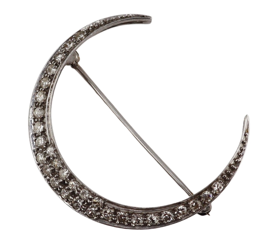 JEWELRY. Platinum and Diamond Crescent Moon: Brooch. Platinum brooch in the form of a crescent moon displaying a total of (30) round brilliant cut diamonds. Apparently unmarked. Total approx. weight of the brooch is 3.8 dwt (gross). From a Larch