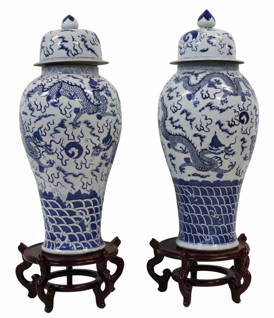 Pair of Large Chinese Blue and White Lidded Urns.: Displaying dragons in flight chasing flaming pearls and surrounded by flames and ruyi clouds. Accompanied by carved wood footed stands. From a Darien, CT estate. Dimensions: 17" x 40" h;