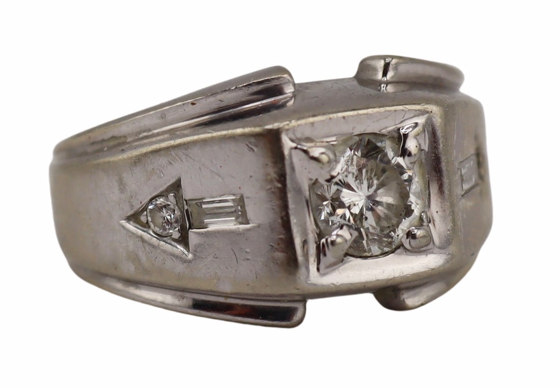 JEWELRY. 13kt Gold and Diamond "Arrows" Ring.: 13kt white gold ring displaying a central flush set round faceted diamond flanked by (2) diamond accented arrows. Each arrow is comprised of a straight diamond baguette and a round faceted diamond. La