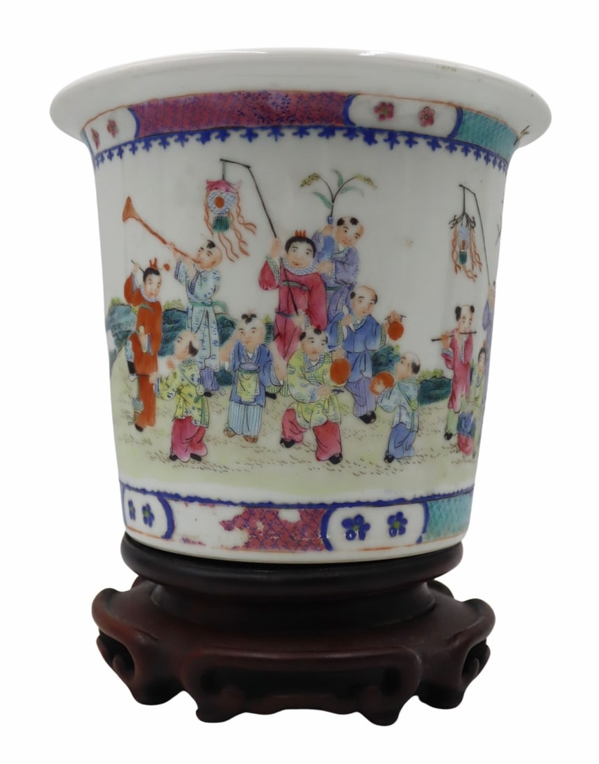 Chinese Famille Rose Enamel Planter on Carved Wood: Base. Chinese Famille Rose enamel decorated planter displaying an outdoor festival or parade. With a mark to the underside. Accompanied by a carved wood stand. From a Great Neck, NY estate.