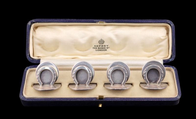 SILVER. Cased Asprey English Silver Horseshoe: Place Card Holders. A cased set of (4) English silver horseshoe place card holders retailed by Asprey. With a city mark of London, maker's mark of Sampson Mordan & Co., and a date letter of 1931.