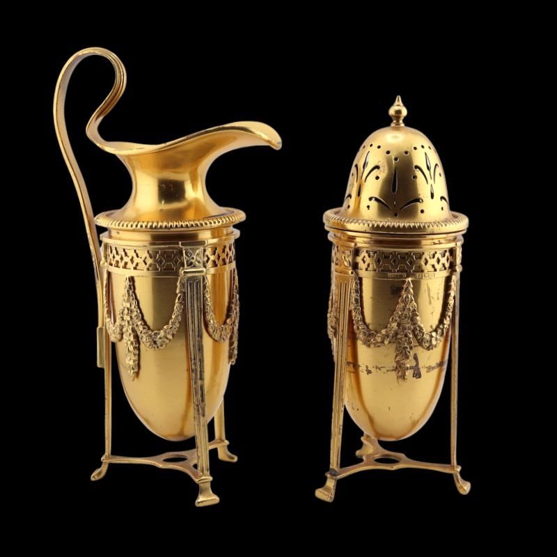 SILVER. Gilt English Silver Creamer & Sugar Caster: A fine monogrammed English gilt silver creamer and sugar caster, each accompanied by a matching gilt silver stand decorated with floral swags. All (4) items bear a city mark of Birmingham, maker's mar