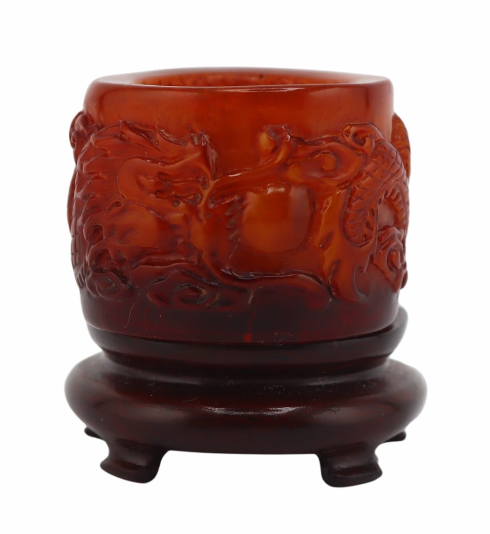 Chinese Carved Amber Archer's Ring.: Chinese carved amber archer's ring displaying a high relief dragon set amongst ruyi clouds. With a carved wood fitted stand. Total approx. weight of the ring is 16.7 grams (gross). From a Great Neck,