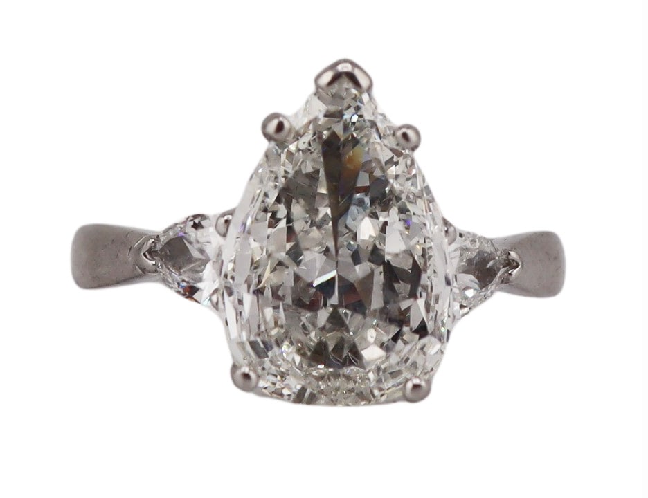 JEWELRY. Platinum and 3.59ct Pear Diamond Ring.: Platinum engagement ring displaying a prong-set 3.59ct pear faceted diamond flanked by (2) smaller pear faceted diamonds. Large diamond measures approx. 9.8mm x 14.5mm. In the process of obtaining a G