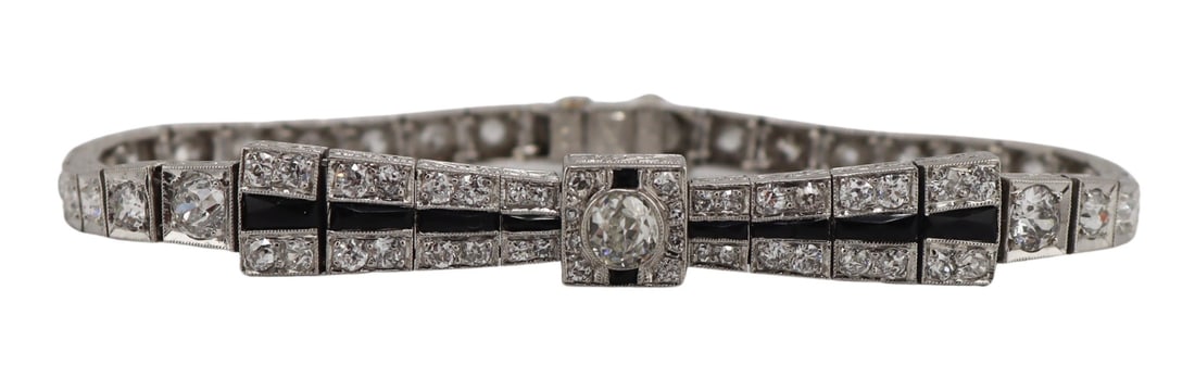 JEWELRY. Art Deco Platinum, Diamond and Onyx: Bracelet. Art Deco platinum line bracelet displaying a central raised Old European cut diamond surrounded by faceted onyx panels and (8) diamonds within a square frame; this central panel is flanked b