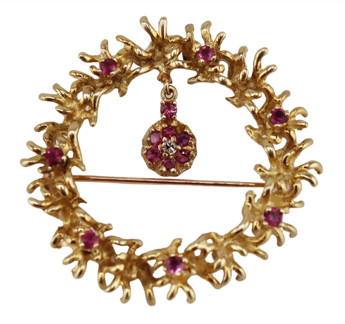 JEWELRY. 13kt Gold, and Ruby Wreath Form Brooch.: 13kt yellow gold wreath form brooch accented by (7) prong-set round faceted rubies and further displaying a ruby accented floral form drop pendant. Stamped, "14K" verso. Total approx. weight