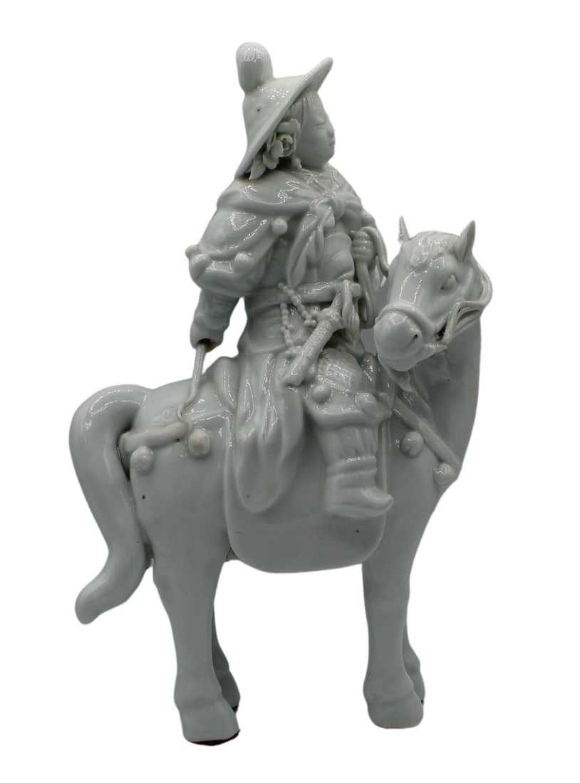 Chinese Blanc de Chine Figure on Horseback.: Chinese blanc de chine figural grouping of a figure on horseback. The figure's left hand holds the reins while the right hand is back. The horse's head is turned to the left. There is a different mate