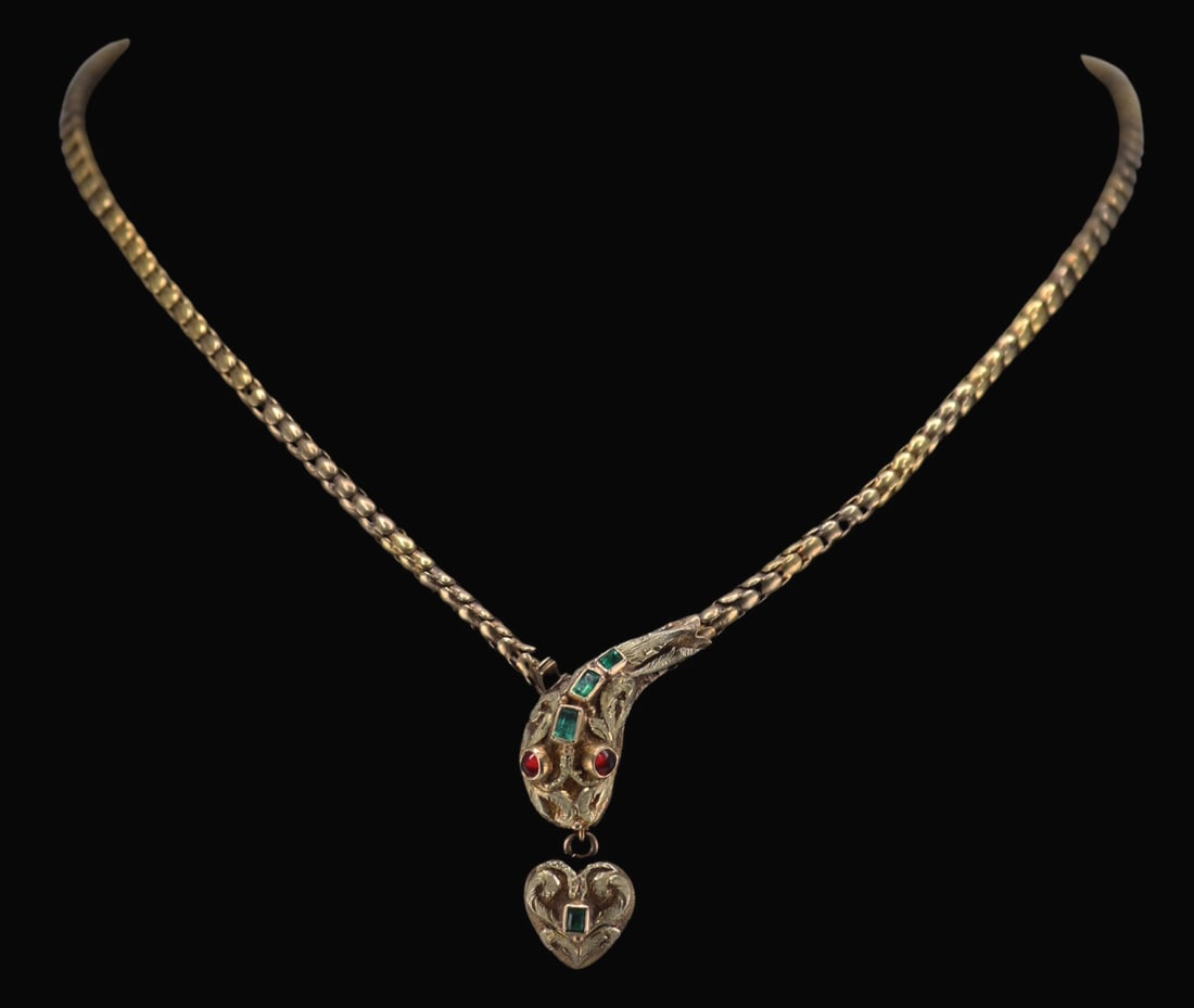 JEWELRY. Victorian Emerald and Garnet Snake: Necklace. Victorian beautifully articulated snake form necklace displaying a snake's head accented by (3) raised bezel set faceted emeralds, and a pair of round garnet cabochon eyes. Further accented 
