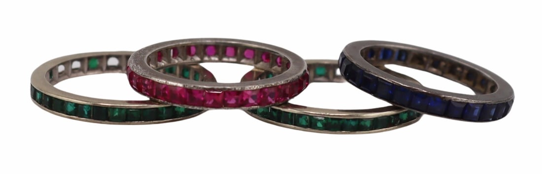 JEWELRY. Gold or Silver and Colored Gem Bands.: Includes (2) Art Deco 13.5kt white gold band rings displaying channel set faceted emeralds - both rings are missing several stones, apparently unmarked, both rings are a size 6 1/2; a silver band ring