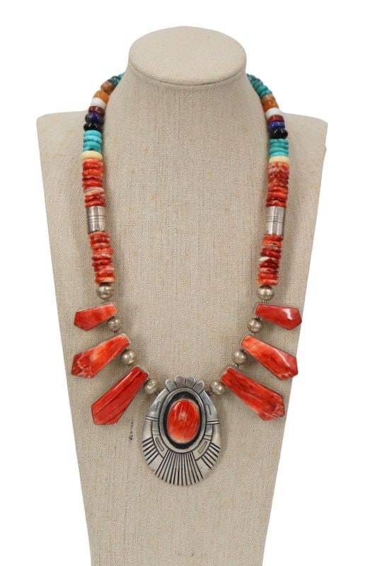 JEWELRY. Tommy Singer Navajo Sterling Necklace.: Southwestern sterling silver necklace by Navajo silversmith Tommy Singer (1940–2014) featuring a graduated design centered by a large sterling silver oval pendant with a polished coral cabochon.