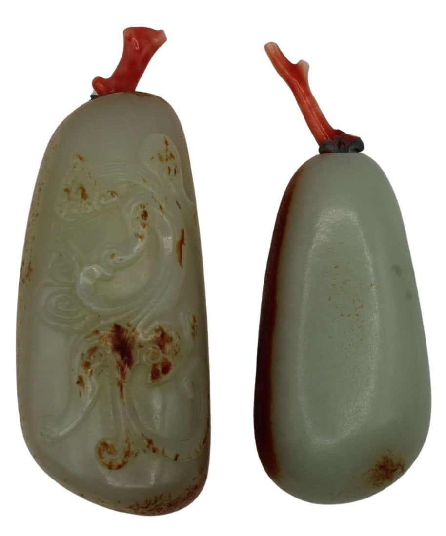 (2) Chinese White Jade 'Pebble' Snuff Bottles.: 2 Chinese 'pebble' snuff bottles carved from white jade with russet skin. The larger is further decorated with incised decoration. Both snuff bottles are accented by coral branch stoppers. Total appro