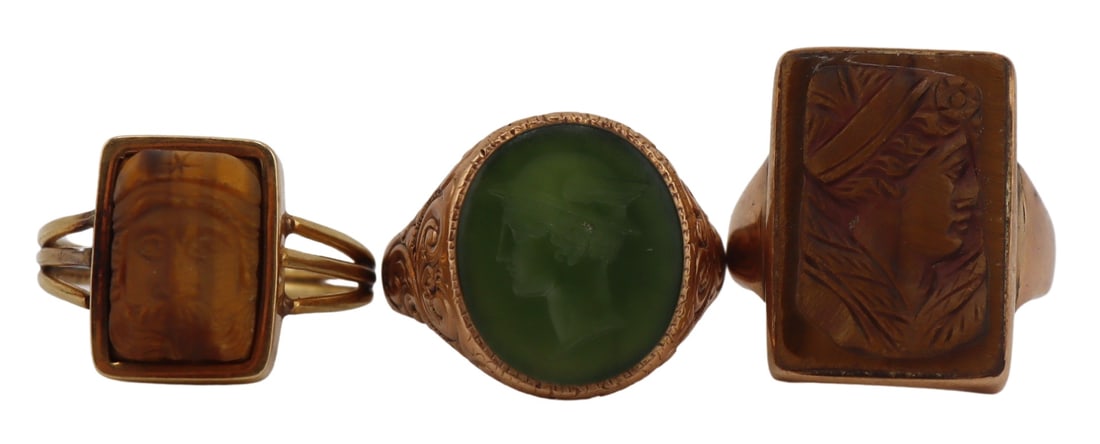 JEWELRY. (3) Assorted Gold and Carved Gem Rings.: Includes a 10kt yellow gold mounted ring with central carved tiger's eye pendant of a God, possibly Hercules, and displaying split shank shoulders, size - 9; a 9ct yellow gold ring with central carved