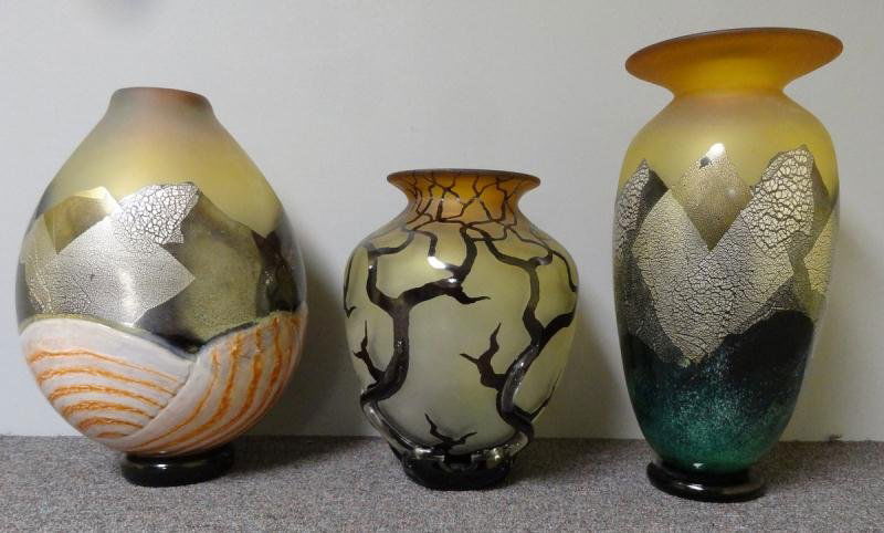 Lot of 3 Glass Vases by Bernard Katz.: All signed. Includes one frosted glass bulbous vase with tree motif in black over frosted amber colored glass. Also with raised clear glass roots. Together with two larger vases with mountain range mo