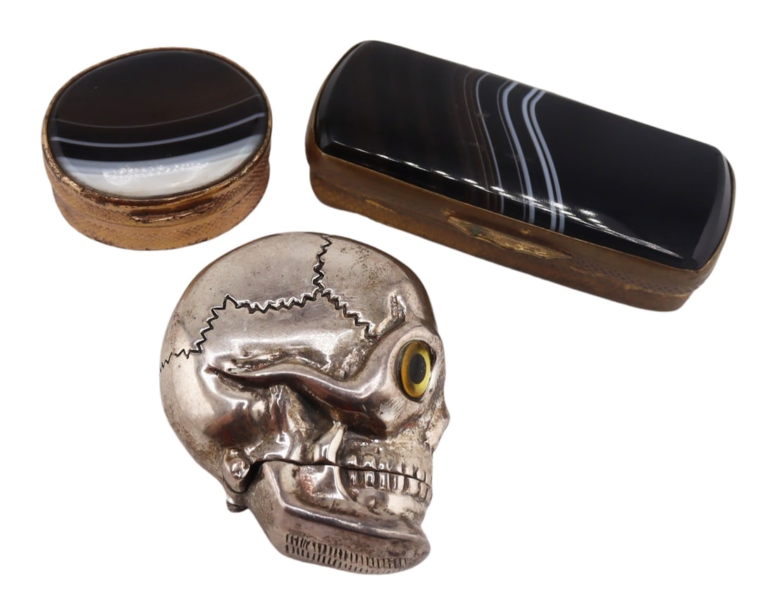 STERLING. Skull Vesta Case and (2) Agate Boxes.: Sterling skull form vesta case with glass eyes and a hinged bottom jaw - stamped, "Sterling". Accompanied by (2) 19th century gilt metal mounted banded agate snuff boxes. Total approx. weigh