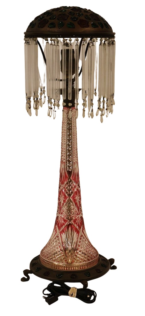 Tall Bohemian Glass Lamp with Bejeweled Shade &: Base red to clear cut glass base with a bronze shade with glass leaf inserts. The base also with glass inserts and raised on claw feet. From the estate of a 50+ year antique dealer specializing in dec