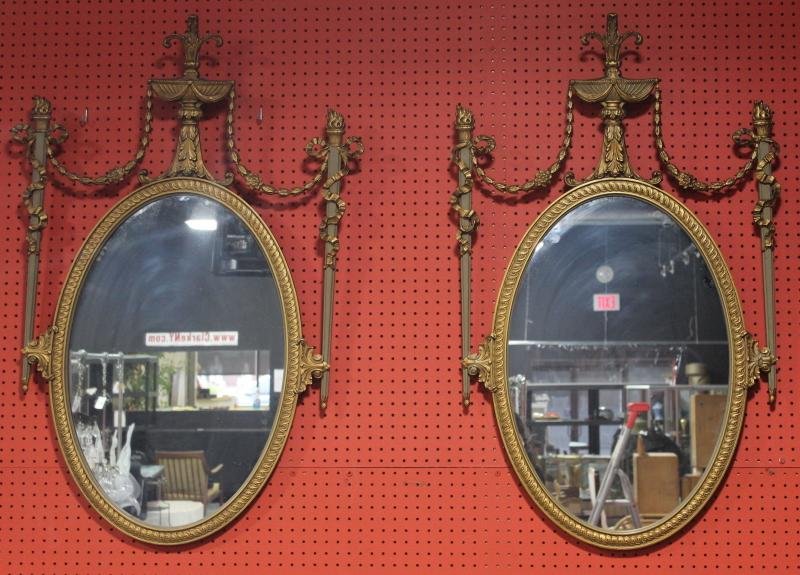 Pair of Gilt Wood Adams Style Oval Mirrors.: Central mirror flanked by torchere forms and urn crown. From a Long Island, NY location. Dimensions: 29" wide x 47" high.