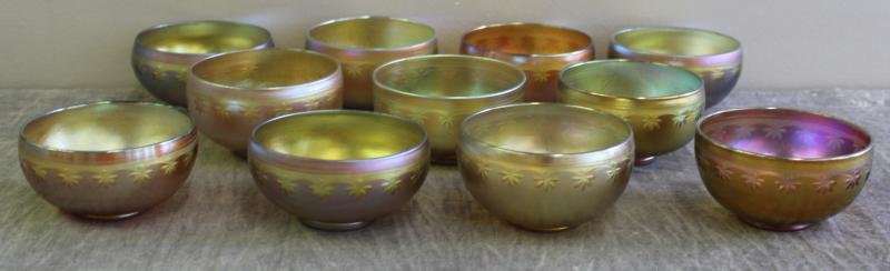 Rare Set of 11 Tiffany Favrile Bowls.: With intaglio cut borders. 10 inscribed on bottom L.C. Tiffany Favrile; one unmarked. Slight variations in size; iridescence and color. From a Scarsdale, NY home. Dimensions: 4.125" diameter x 2.25" h