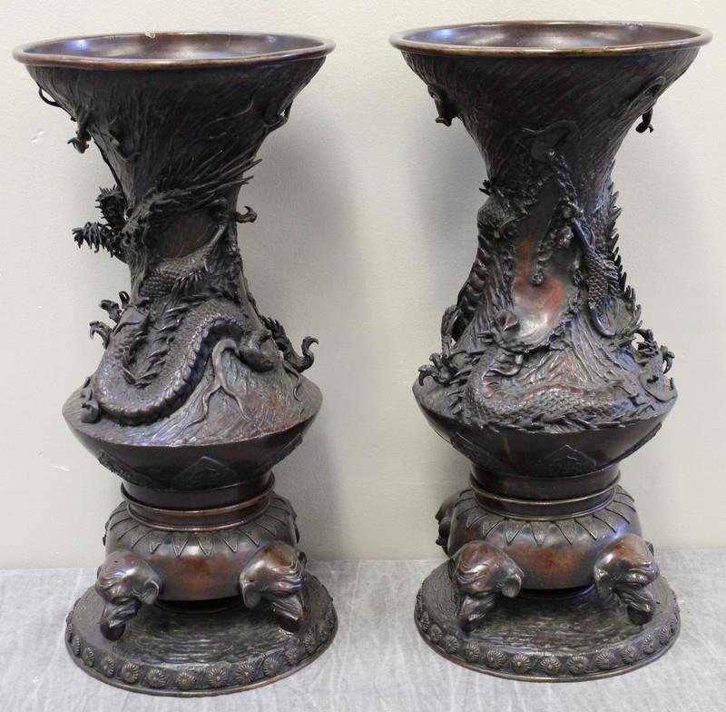 Pair of Asian Bronze Urns with Dragon Motif and: Elephant Head Base. Good quality. Unmarked. From a Connecticut estate. Dimensions: 8.75" diameter of top x 17.75" high. Condition: One base detached but an easy clean repair.