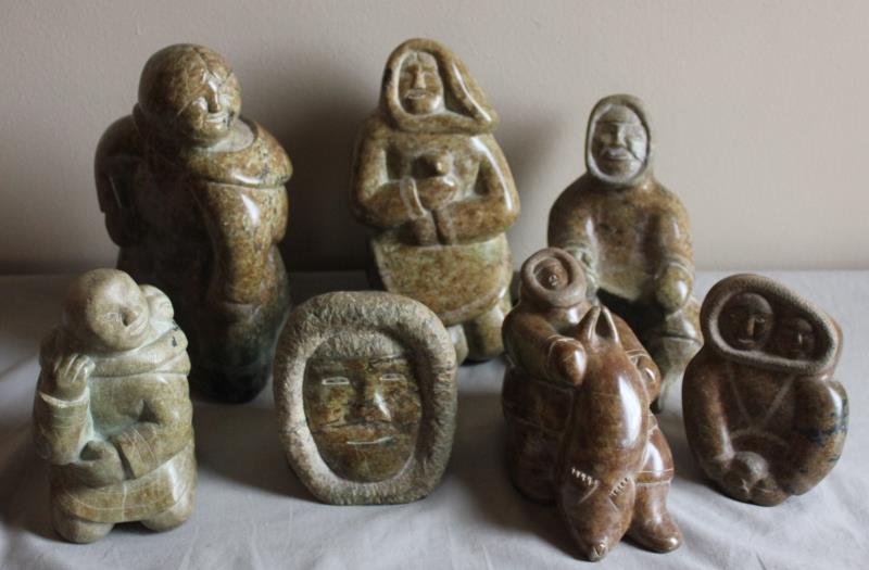 7 Piece Inuit Figural Lot.: Includes a child with animal - 10" h, an old woman - 13" h, 2 faces - 7" h, a single face 7.5" h, a figure with baby- 12" h, a figure kneeling 8" h, and a figure seated- 7" h. From a West 57th St. NYC