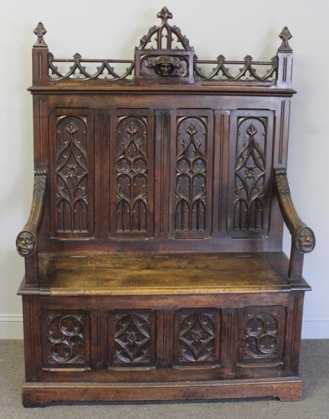 Gothic Revival Walnut Hall Bench.: A walnut lift seat hall bench with typical Gothic elements and well carved male heads - all different. From a Bronxville, NY estate. Dimensions: 46" w x 18.375" d x 66" h. Condition: Good.