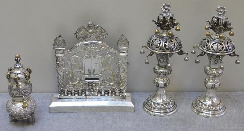 JUDAICA. Miscellaneous Judaica Grouping.: Includes a pair of silverplate torah crowns with floral finials, a silverplate menorah with lion rampant decoration and inscriptions to base, and an English torah crown - with a maker's mark of R&T. A