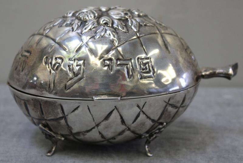 JUDAICA. .800 Silver Etrog Box.: Egg form footed Etrog box with repousse fruit and floral design to lid, and Hebrew inscription. With gilded interior. Stamped 800 and 30 on bottom. Accompanied by a dried etrog in a nest of hair? Tota