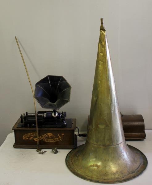 Edison Home Cylinder Phonograph.: Includes crank, another reproducer, 50 plus records, a brass horn, a tin horn and horn rod. From a white Plains, NY estate. Dimensions: 18" long. Condition: Not working, dents to horns.