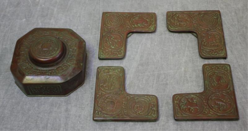 Tiffany Bronze Inkwell in the Zodiac Pattern.: Fine original patina, numbered "842" and signed "Tiffany Studios / New York", with a set of 4 blotter corners, numbered "996", same signature. Dimensions - Inkwell 4.125" x 4.125" x 2"; the corners ea