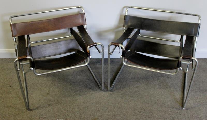 Midcentury Pair of Wassily Chairs.: One with black and brown straps, other all black straps. Leather. Unmarked. From a New Rochelle, NY estate. Dimensions: 28.5" w x 30.5" d x 26.5" h. Condition: Leather to both with abrasions and losse