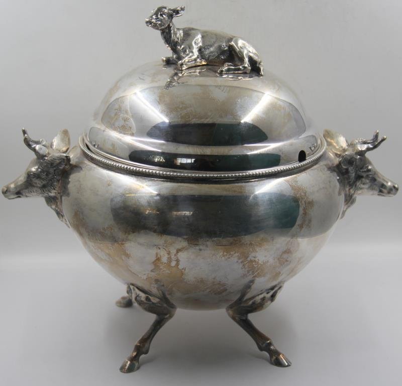 SILVER-PLATED. Silver-plate Cow Motif Tureen.: Wonderful silver-plated tureen with hoofed legs, cow head handles, and calf finial. With familial crests to body of vessel. From a Rye Brook, NY home. Dimensions: 12" w x 8.5" d x 10.5" h. Condition: 
