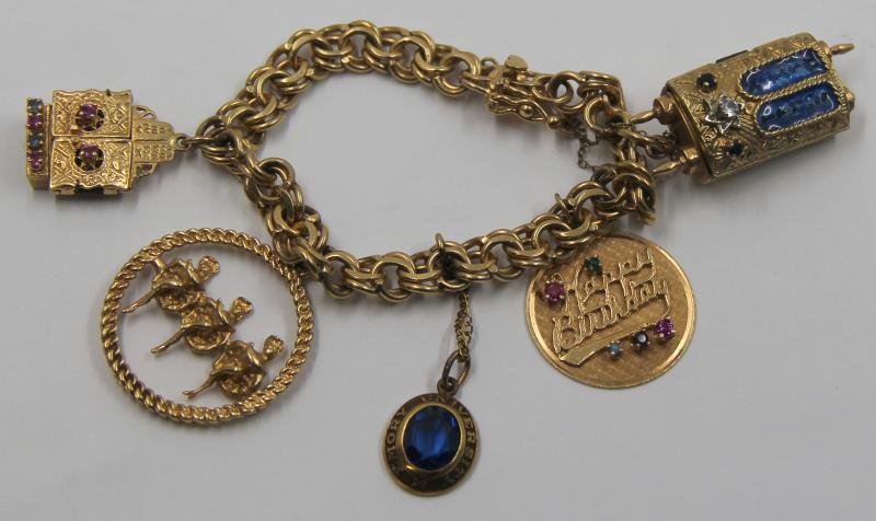 JEWELRY. 14kt Gold Charm Bracelet with 5 Charms.: Comprised of a 14kt yellow gold charm bracelet; a 14kt gold, enamel, diamond, and sapphire Torah scroll amulet charm that opens to reveal a scroll; a 14kt gold "Happy Birthday" charm with colored gems