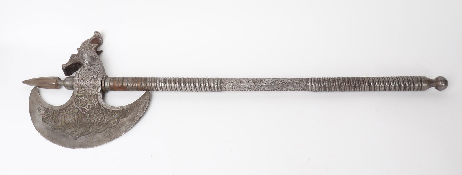 Gilt Indo-Persian Axe w/ Zoomorphic Head: India or Pakistan, Indo-Persian 20th century fine large scale axe in steel with twisted groove shaft and top central spike, Axe face in crescent moon shape with Islamic text engraved and lightly gilt,