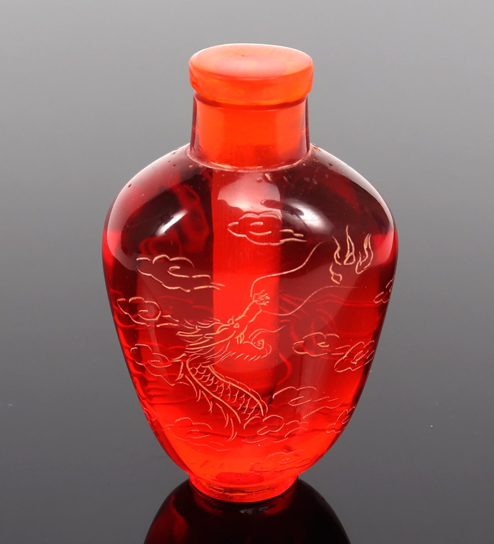 Chinese Cranberry Red Snuff Bottle: Dragon in flight etched to the front of the snuff bottle, surrounded by clouds with his mouth open, ready to let out flames. Size 2 3/4" H