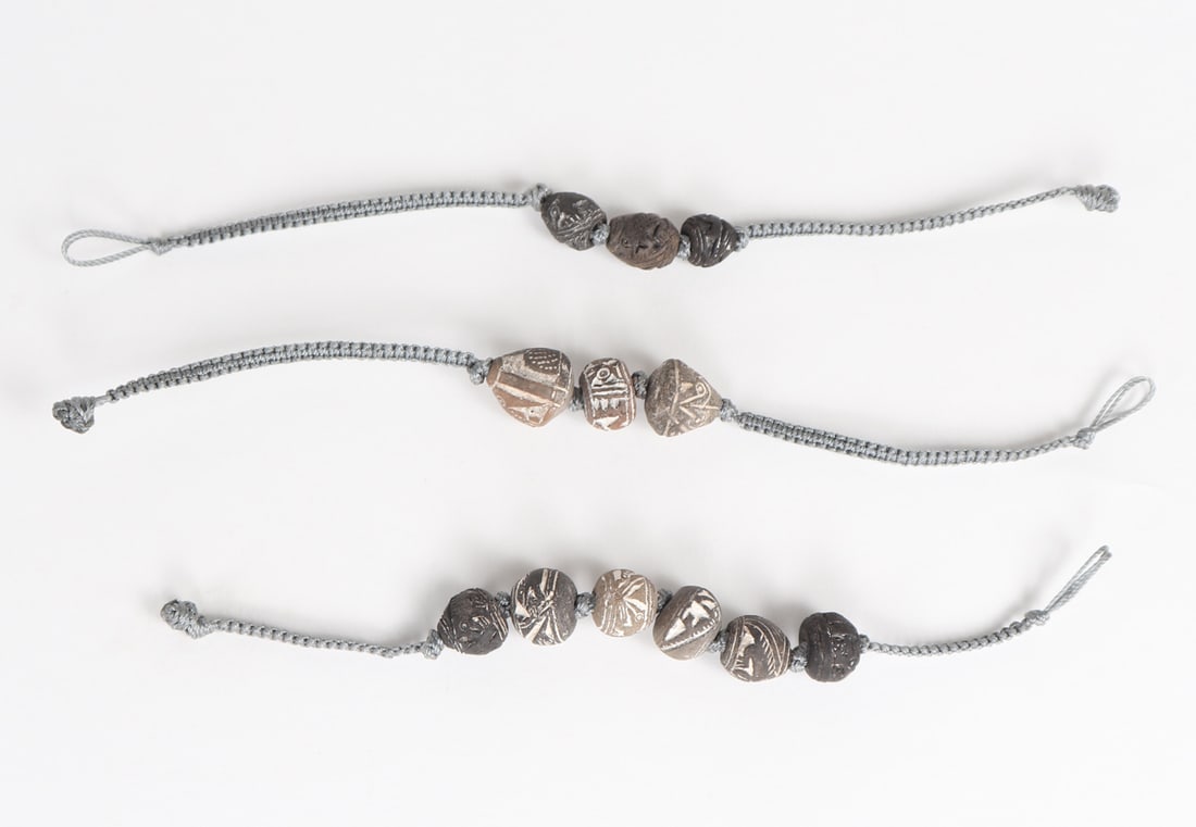 Group of Three Ecuadorian Spindle Whorl Bracelets: Three beautifully strung bracelets with Ecuadorian terracotta spindle whorl beads featuring animal and avian designs as well as geometric incised designs. Size of largest bracelet 8"