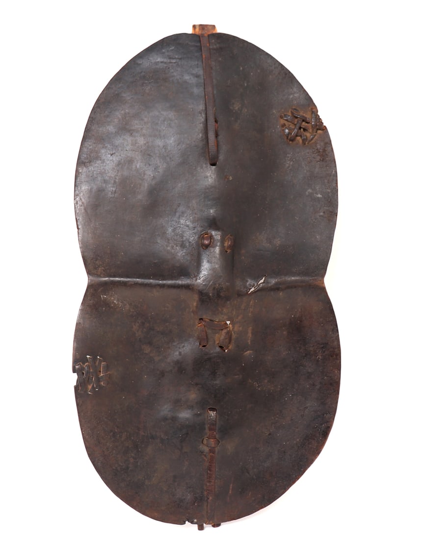 African Animal Hide Shield: Well crafted old African hide shield with cross section in a strong light wood secured with leather straps. Dark heavy patina throughout. Handle is wrapped in leather for firm and solid grip while def
