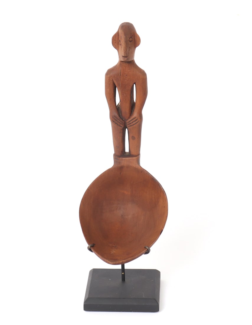 Filipino Bulul Spoon: Skillfully carved from a single piece of light wood, with a deep ovoid bowl. Bulul stands with his hands at his thighs, his face carved deeply with incised eyes and notched protruding nose. Size 9 3/4